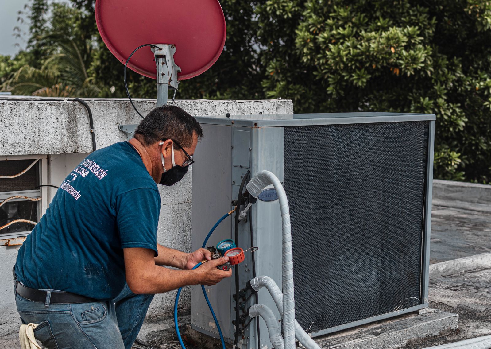 Technician using a manifold gauge to check refrigerant levels on an outdoor air conditioning unit